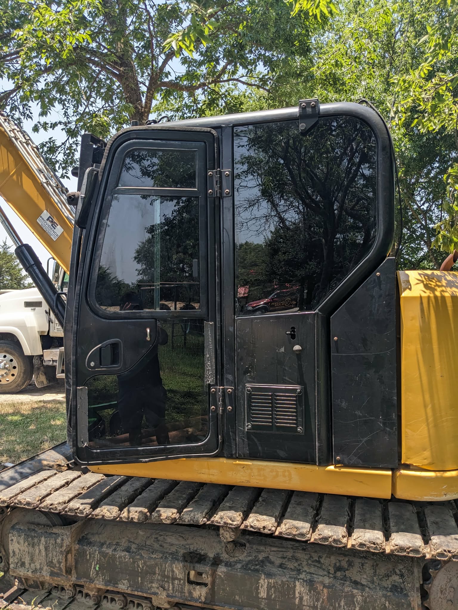 Excavator cab door with tinted windows at a job site